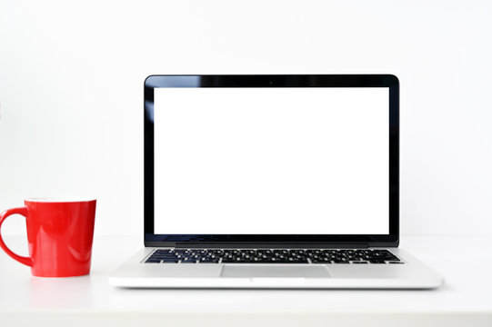 blank screen Modern laptop computer with Red coffee cup on wood table in office view backgrounds