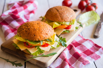 Delicious sandwiches with cheese, lettuce, vegetables and arugola on white background