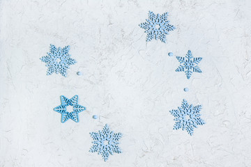 Openwork wooden blue snowflakes on light shiny background with copy space. Beautiful decoration for Christmas or New Year. Top view. Flat lay.