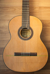 Acoustic guitar resting against a wooden background