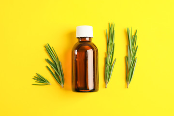 Flat lay composition with rosemary oil and leaves on yellow background, space for text