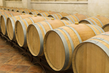 Wine barrels stacked in the cellar of the winery. Wine barrels in wine-vaults.