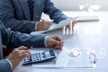 Two businessmen in a meeting room are deeply reviewing financial statements and reports for a...