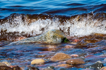 Coloured pebbles at the shoreline with water and waves