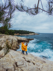 Fototapeta premium smiling couple in yellow raincoats at the edge of the cliff looking at sea