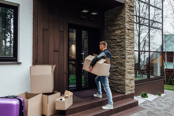 Moving. Young man with carton boxes in new apartment.