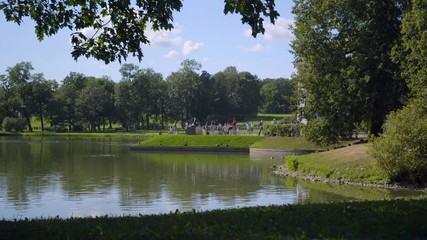 Tourists walk on a shore of a Great Pond in Alexandrovsky Park , feed ducks