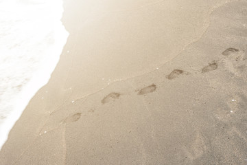Fototapeta na wymiar Footprints in the sand on sea coast. Vacation concept