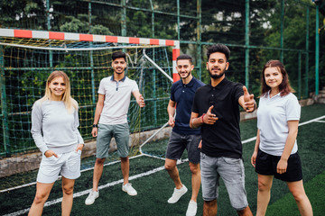 Young team of football players posing tothe photo on field.