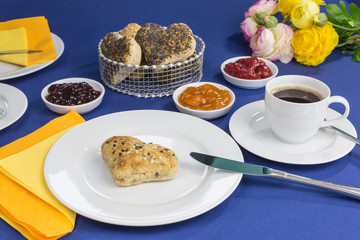 breakfast table with freshly baked heart shaped buns, different jams and coffee