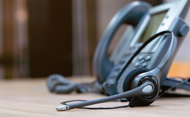 close up soft focus on headset with telephone devices at office desk for customer service support...