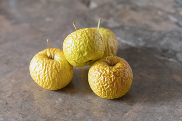 Wrinkled yellow old apples lies on the table top.