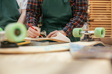 Two unknown male carpenters make a skateboard on an exclusive order. Concept hobby for youth and handmade