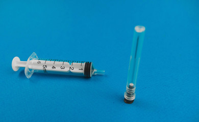 medical syringe with a needle lying on a blue background