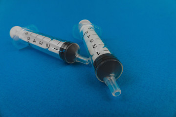 two medical syringes lying on a blue background