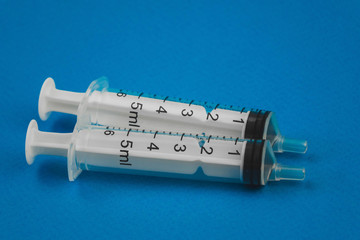 two medical syringes lying on a blue background
