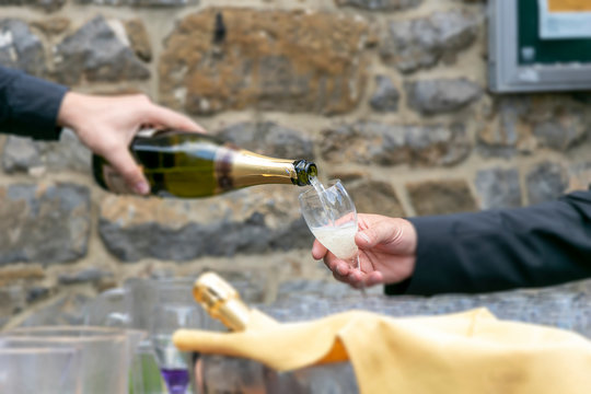 close up of hand pouring champagne in the glass for celebrated wedding party outdoor, blurred image.  