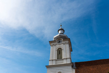 Obraz premium Clock on focus on catholic church, vibrant blue sky with white clouds, copy space.