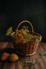 Fototapeta na wymiar Autumn composition with yellow tansy flowers in a wicker basket and pears on a wooden background
