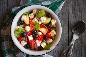 Delicious greek salad with feta cheese and olives in a white bowl