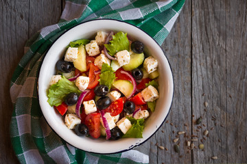 Delicious greek salad with feta cheese and olives in a white bowl