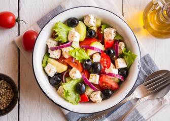 Delicious greek salad with feta cheese and olives in a white bowl