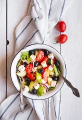 Delicious greek salad with feta cheese and olives in a white bowl