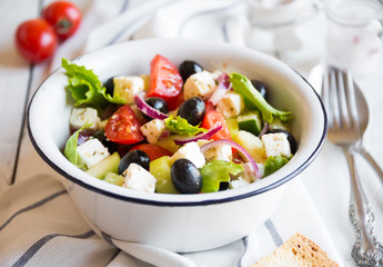 Delicious greek salad with feta cheese and olives in a white bowl
