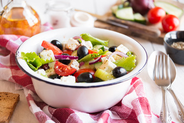 Delicious greek salad with feta cheese and olives in a white bowl