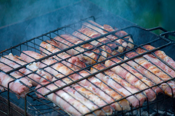 Meat barbecue. Sausages with cheese spun in bacon on a metal grill close-up.