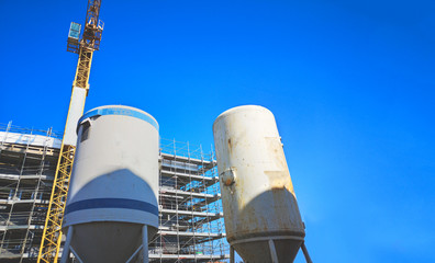 mortar silos at construction site with crane and blue sky
