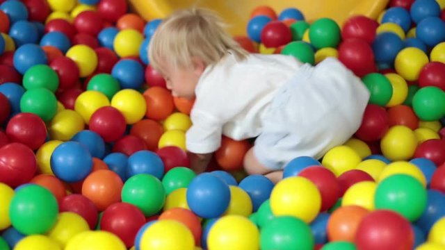 Little toddler child, boy playing in children playground indoors, kid plays in kindergarden playground