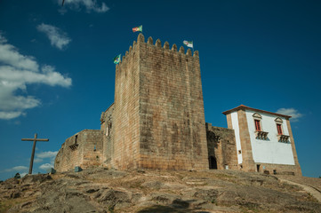 Castle and square tower over rocky hill with cross