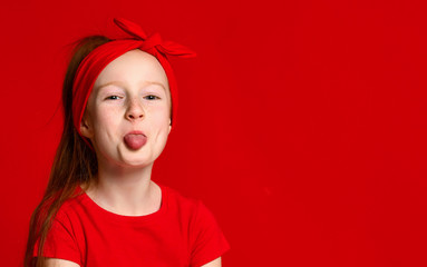 Cute funny red-haired girl in a red bandage on her hair and a red T-shirt jokingly shows your...