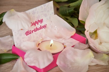 happy birthday greeting candle with flame and peony petals