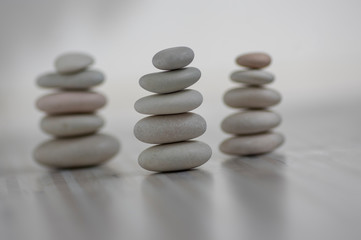 Fototapeta na wymiar Harmony and balance, three cairns, simple poise pebbles on wooden light white gray background, simplicity rock zen sculpture