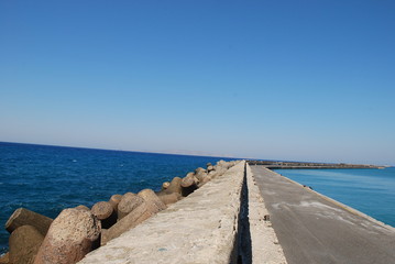 Fototapeta na wymiar Long stone pier stretching into the blue sea