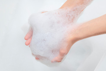 A pile of foam in the hands of a teenager in the bathroom