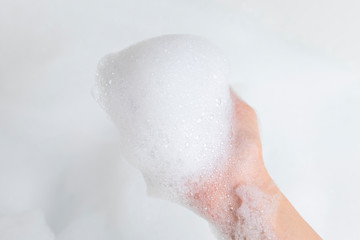 Hand with foam while bathing and cleaning the bathroom