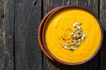 pumpkin soup on wooden background, top view