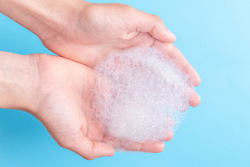 Fototapeta premium Two hands hold a bunch of foam while washing their face and body