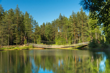 Fototapeta na wymiar Blue lake in forest, Russian landscapes, beautiful nature. Beautiful bridge.