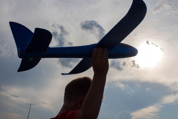 a boy playing with a airplane in the street