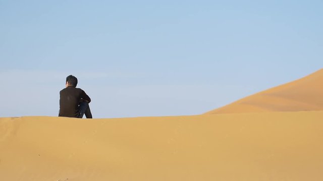 Camel shepherd sitting in Erg Chebbi desert