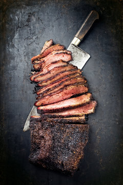 Traditional smoked barbecue wagyu beef brisket offered as top view with knife on an old rustic board with copy space