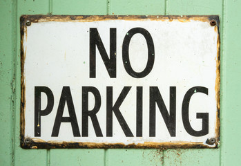 Old No Parking sign on green patina wooden background