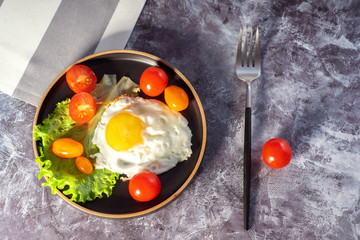 Fried eggs in a pan with cherry tomatoes and coffee for breakfast on a light background on a sunny day.