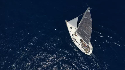 Deurstickers Aerial photo of sail boat cruising open ocean deep blue sea © aerial-drone