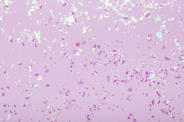 Glowing mica sparkles on pastel violet trendy background. Festive abstract backdrop with confetti. Flat lay.