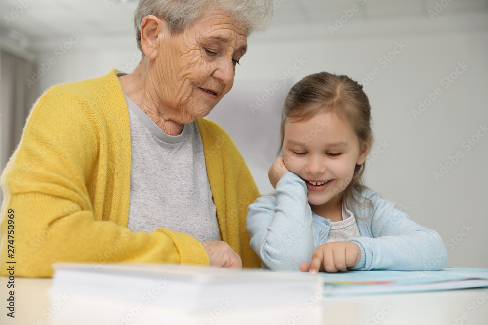 Canvas Prints Cute girl and her grandmother reading book at home